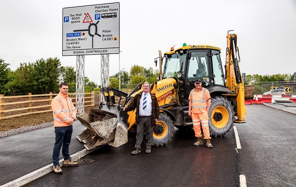 Photo of three people standing in front of a bulldozer.