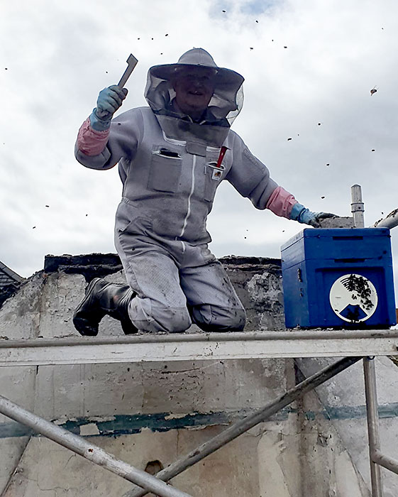 Photo of an apiarist on a roof.
