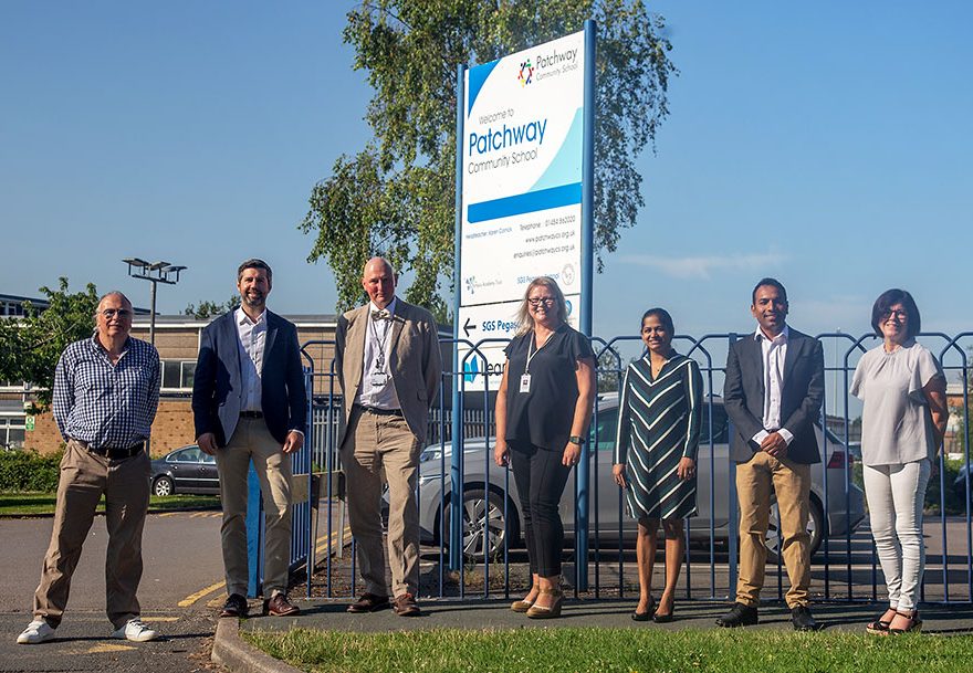 Photo of a group of seven people standing at the entrance to a school.